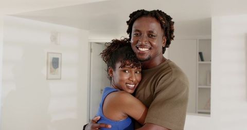 Young couple embracing in bright modern home, warm smiles and cozy moment