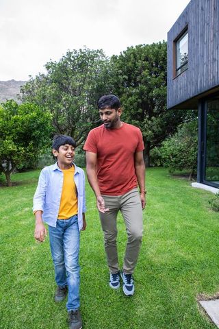 Asian Father and Son Enjoy Outdoor Walk in Modern Yard