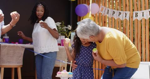 Grandmother and Granddaughter Sharing Cupcakes at Birthday Celebration