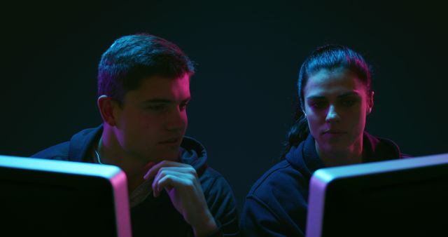 Two young Caucasian men focused on their computer screens, in a dark room - Download Free Stock Photos Pikwizard.com