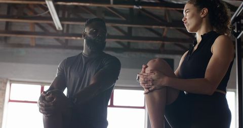 Diverse Workout Partners Stretching in Gym for Wellness