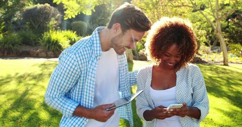 Young Couple Enjoying Digital Technology in Sunny Park