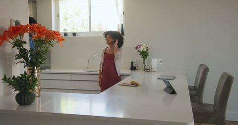 Woman Smiling and Talking on Smartphone in Modern Kitchen