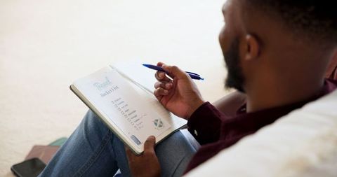 Man writing travel bucket list at home