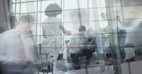Team collaborating in glass atrium with motion blur and reflections, modern office lounge
