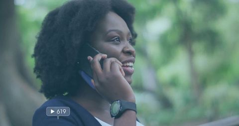Cheerful Woman Chats on Smartphone Outdoors in Peaceful Park