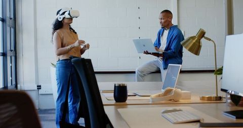 African American team testing VR and collaborating with laptop in open-plan office
