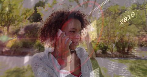 Woman Talking on Smartphone in Sunlit Garden with Futuristic HUD 2010 Overlay