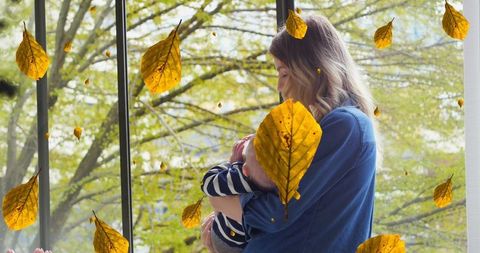 Caucasian Mother Feeding Baby with Autumn Leaves