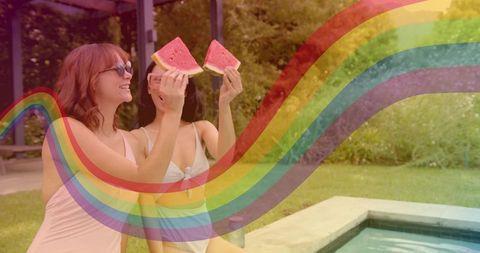 Two women holding watermelon slices by backyard pool with colorful rainbow overlay