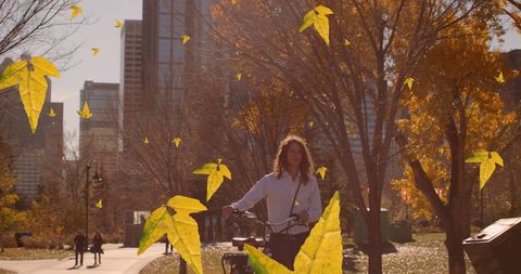 Man Biking Through Autumn Leaves in City Park - Download Free Stock Images Pikwizard.com