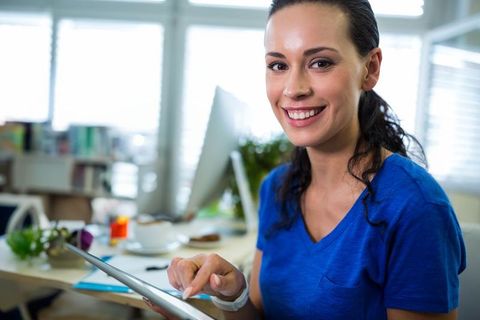 Smiling Professional Woman Using Tablet at Office Desk