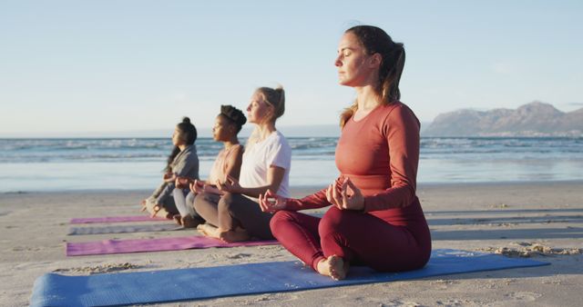 Group of diverse female friends meditating at the beach. healthy active lifestyle, outdoor fitness and wellbeing.