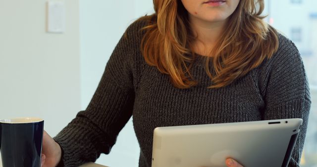 Woman using digital tablet while having coffee at home