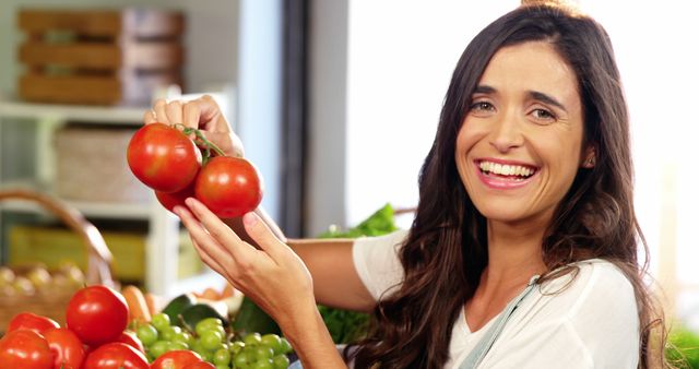 This vibrant image of a woman holding fresh tomatoes at a market can be used for promoting grocery stores, farmer's markets, healthy eating, and organic produce. Ideal for blogs, websites, and advertisements focused on nutrition and healthy lifestyles.
