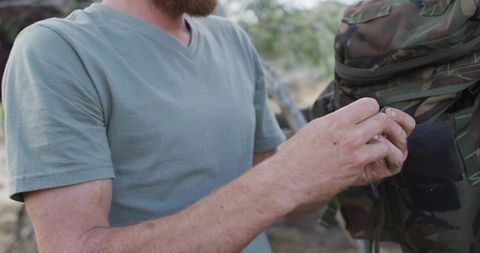 Outdoor enthusiast handling camouflage jacket in forest