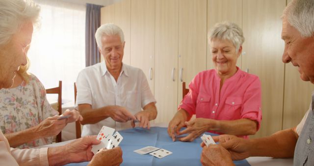 Group of seniors enjoying a card game together around a table in a well-lit room. This setting emphasizes happiness, friendship, and the joy of staying socially active during retirement. Use for community center promotions, retirement living marketing, or any content highlighting the benefits of social engagement for the elderly.