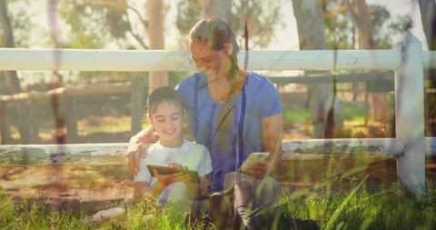 Mother and daughter enjoying digital devices outside