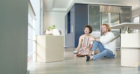 Happy couple sitting among boxes, discussing ideas for new home