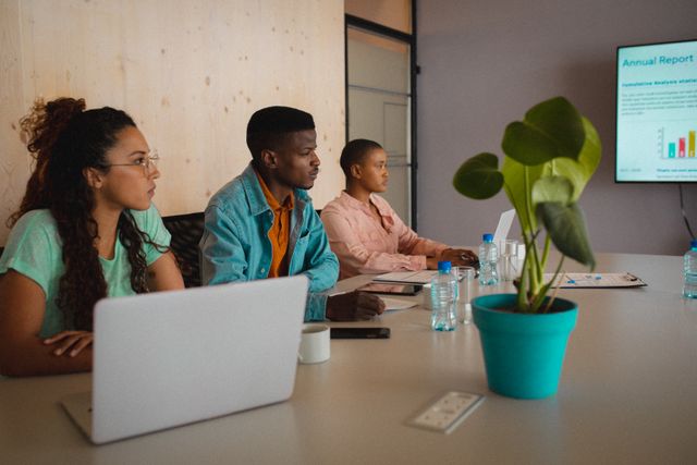 Multiracial business team discussing an annual report in a modern, creative office. Ideal for marketing materials on diversity in the workplace, business meetings, office environment, and corporate strategy discussions.