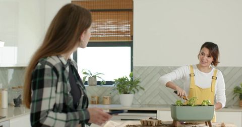 African american woman planting indoor herb garden on bright modern kitchen counter