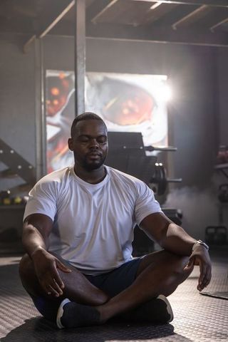 African man meditating in gym practicing breathwork for recovery, focus and strength