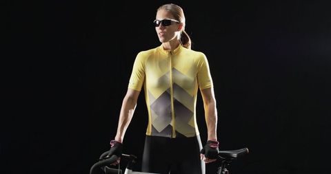 Confident Cyclist in Yellow Jersey Holding Bicycle on Dark Background