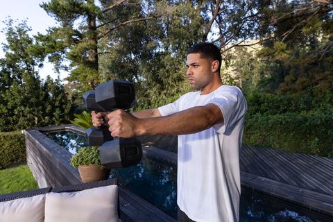 Man doing outdoor dumbbell workout on deck near pool
