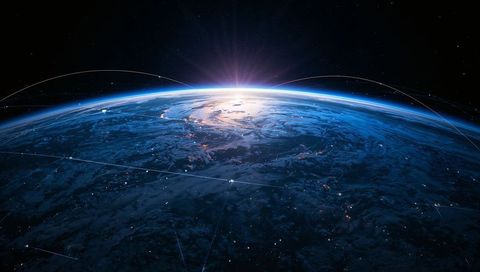 Sunrise over earth from orbit with networked satellites and city lights connecting globe