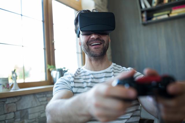 Happy man using virtual reality headset and playing video game at coffee shop