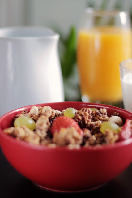 Ideal for promoting a healthy lifestyle, this image highlights a nutritious breakfast consisting of granola, fresh fruits such as berries and grapes, a glass of orange juice, and milk. Suitable for advertisements, health blogs, nutrition guides, food magazines, and cafes.