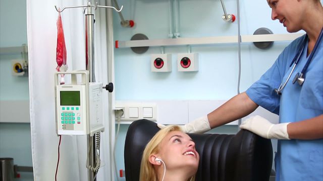 Nurse attending to a blood donor in a hospital ward, ensuring patient comfort and care during the blood transfusion process. Can be used in materials related to healthcare services, hospital environments, blood donation campaigns, patient care promotion, and medical staff training visuals.