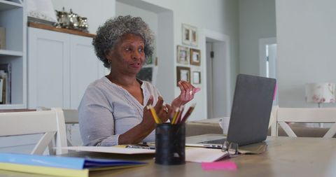 Senior Woman Engaged in Laptop Video Chat at Home, Office Setting