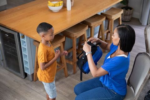 Mother Organizing Boy's Backpack in Kitchen