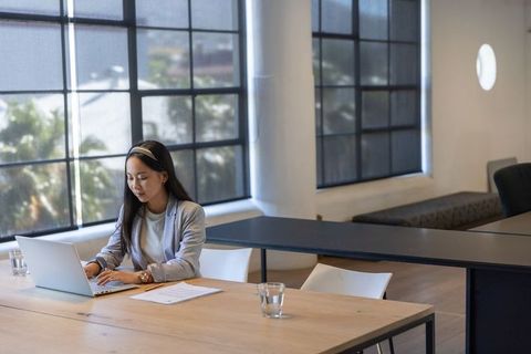 Asian Businesswoman Typing on Laptop at Modern Office Workspace