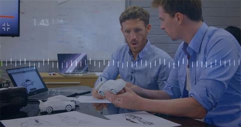 Designers holding car prototype reviewing sketches in automotive design collaboration