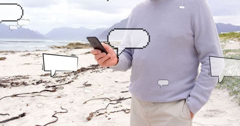 Man Browsing Smartphone with Speech Bubbles on Scenic Beach