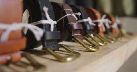 Handcrafted leather belts neatly aligned on shelf in workshop