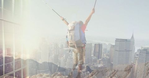 Double exposure of triumphant hiker over cityscape