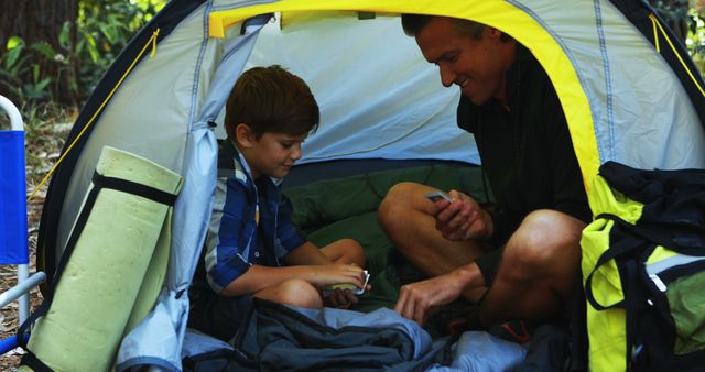 Father and son enjoying camping adventure in tent - Download Free Stock Images Pikwizard.com