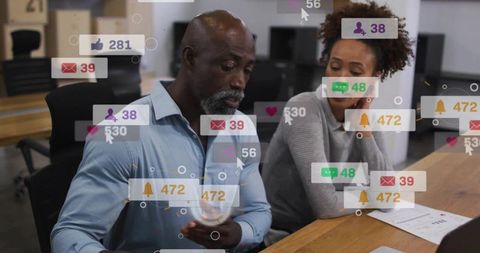 Colleagues managing digital notifications on mobile device in modern open-plan workspace