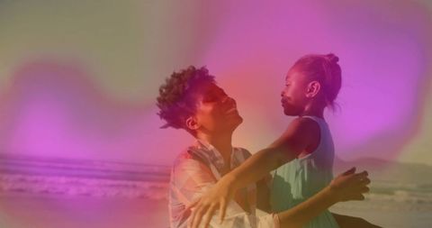 Mother Lifting Daughter by Ocean with Soft Pastel Glow