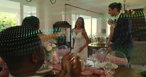 Smiling bride greeting guests at intimate home wedding reception with candlelit table