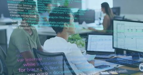Woman Reviewing Code on Dual Monitors in Collaborative Open-Plan Office