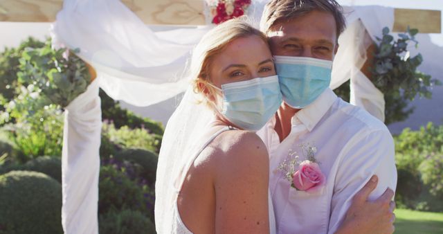 Portrait of happy caucasian newly wed couple touching heads at altar, wearing face masks. romantic summer wedding coronavirus covid 19 pandemic.