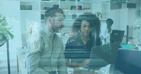 Multiracial coworkers discussing laptop with digital interface overlay