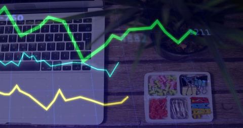 Laptop workspace with analytics graphs overlaying wooden desk and office supplies