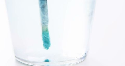 Close-Up of Paintbrush Dipping in Water Creating Aquatic Ripples