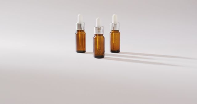 Three amber glass bottles with white dropper caps are neatly arranged on a white background. These bottles are commonly used for essential oils, skincare products, or apothecary solutions. The minimalistic style is perfect for product presentation, retail displays, or promotional materials for natural health products.