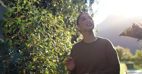 Asian woman enjoying sunshine in lush garden setting